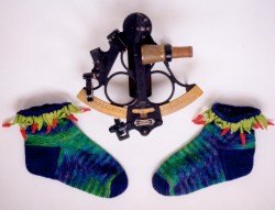 These socks are knitted of hand-dyed merino in a bright blue-purple-green colourway, with lime-green foliage and hot red peppers along the tops.