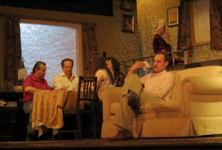 (Image: Family Members are Seated Variously on the Couch,
  at the Dining Room Table, and on an Upstairs Landing