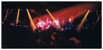 (Image: Rick Derringer in the Spotlight with the Band Behind)