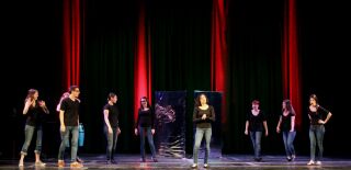 (Image: The Cast Downstage of the
  Mirrors with Red Columns of Light Behind)